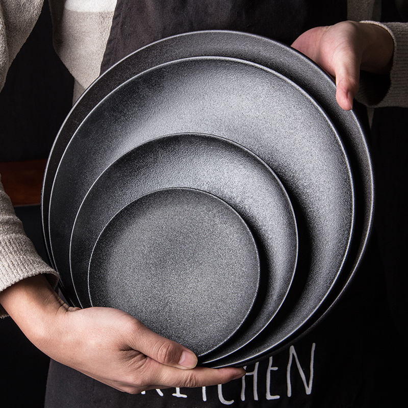 Stacked Matte Grey Ceramic Round Plates Held in Hands